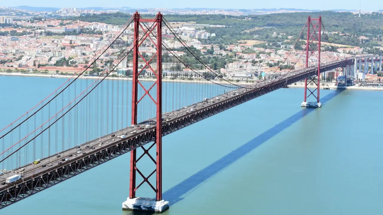 El puente 25 de Abril en Lisboa, con sus icónicas torres rojas, cruza el río Tajo. ¿Cuanto mide el puente de Lisboa? Es un coloso de ingeniería.