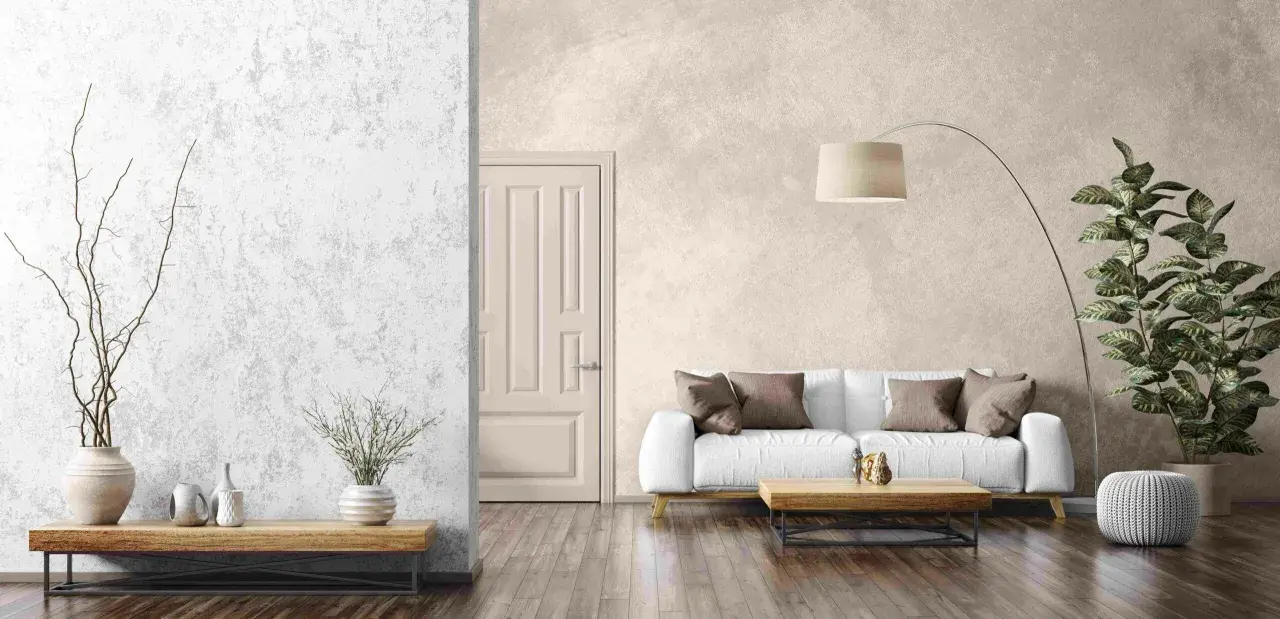 Un salon moderne avec un mur texturé en enduit décoratif, un canapé blanc, une table basse en bois et une plante verte.