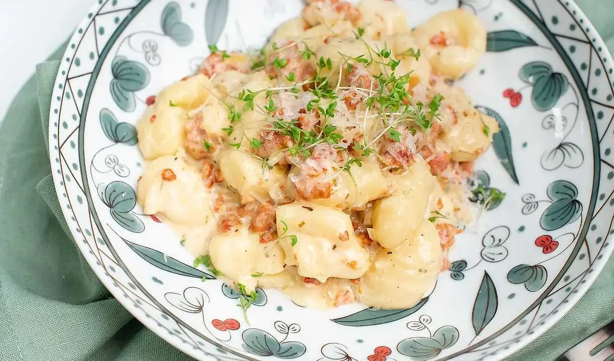 Krämiga gnocchi med salsiccia, toppade med riven ost och färska örter. En härlig rätt som passar perfekt för en mysig middag.