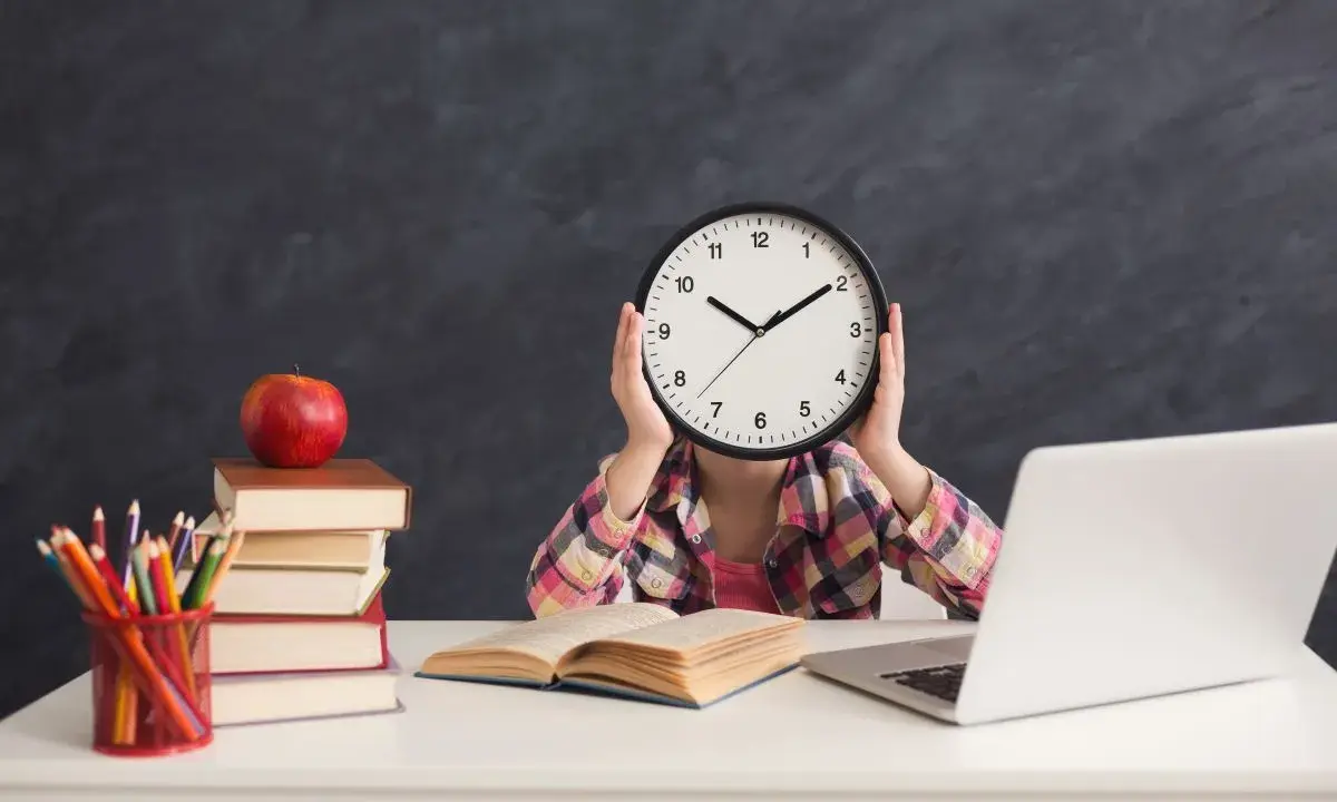 Dziecko z zegarem zamiast twarzy, stos książek, jabłko i laptop. Sierpień godziny pracy, nauka i przygotowania do szkoły.