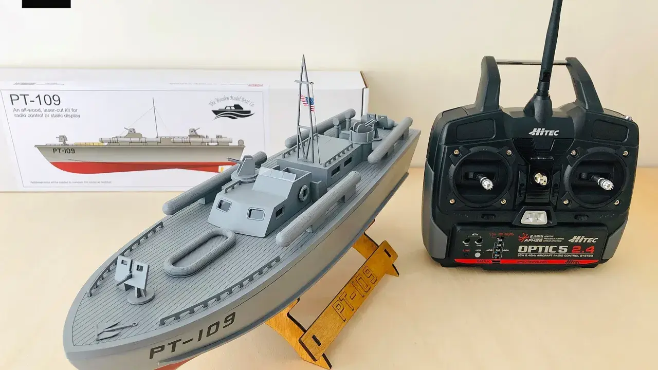 Modell eines Patrouillenboots PT-109 auf einem Holzständer, daneben eine Fernsteuerung.