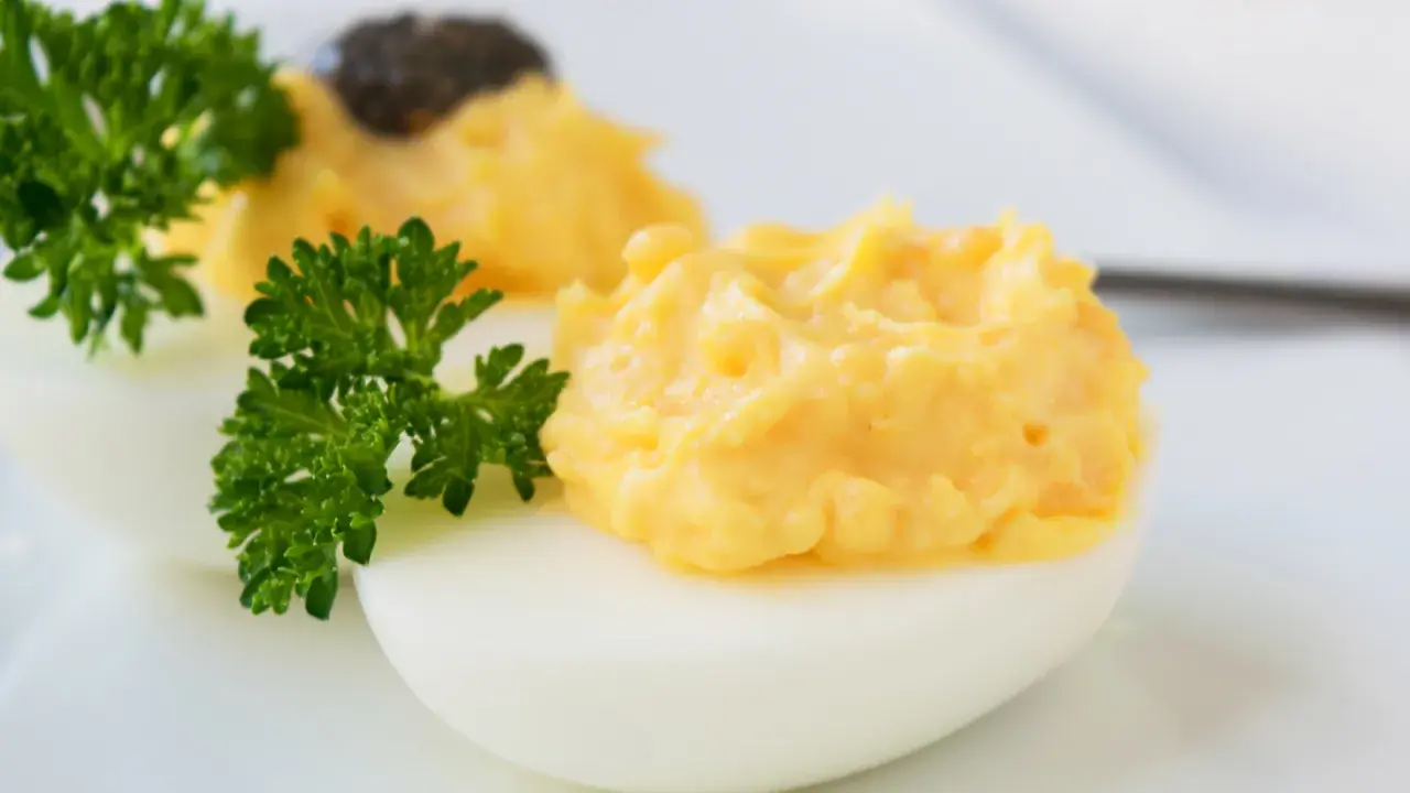 Zwei appetitliche russische Eier traditionell, gefüllt mit einer cremigen Eigelbmasse und garniert mit Petersilie.
