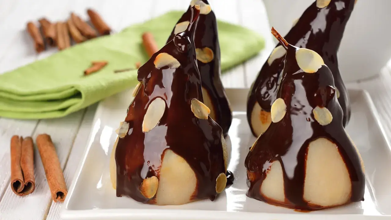Poires pochées nappées de chocolat noir et d'amandes effilées, une délicieuse recette de poire Belle Hélène.