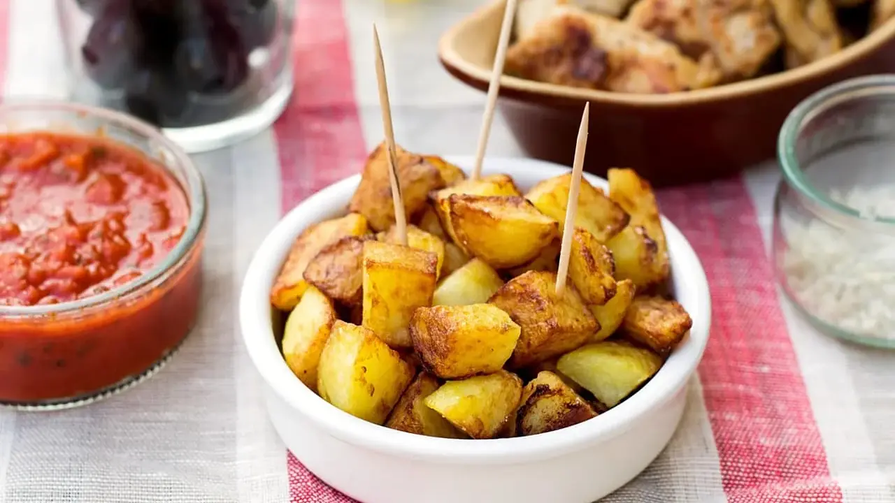 Patatas bravas dorées, servies avec une sauce tomate épicée et des olives. Un délice pour l'apéro !