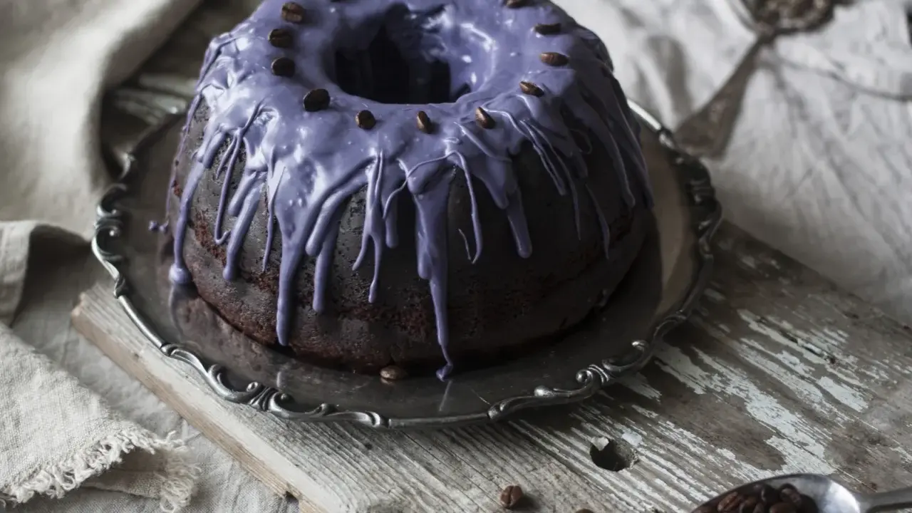 Mörk chokladkaka med lila glasyr och kaffebönor, perfekt för ett chokladkaka recept.