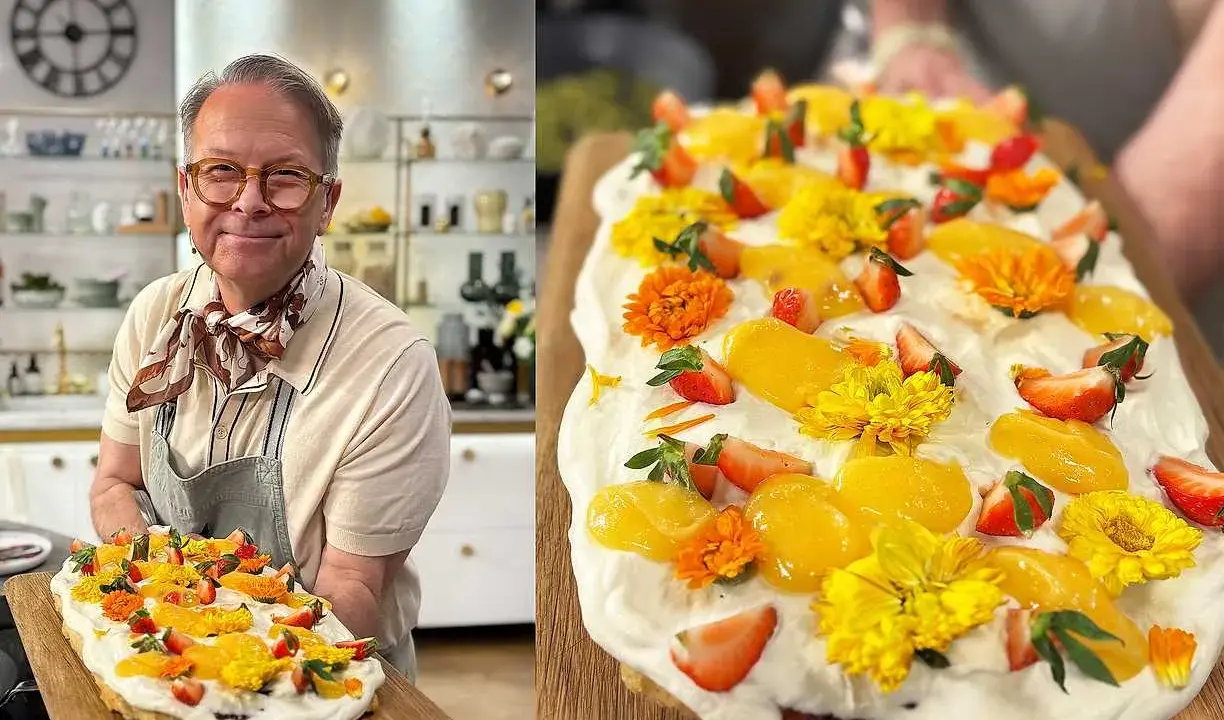 En glad man håller upp en vacker påsktårta i långpanna, dekorerad med grädde, jordgubbar, aprikoser och gula blommor.