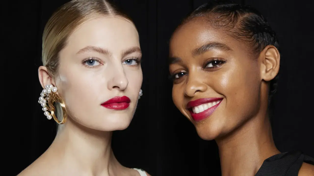 Dos modelos lucen un maquillaje para boda con labios rojos vibrantes y piel radiante. Una lleva un pendiente de perlas, la otra sonríe.