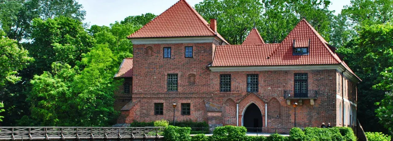 Zamek w Łęczycy, jedna z głównych atrakcji regionu, otoczony zielenią.