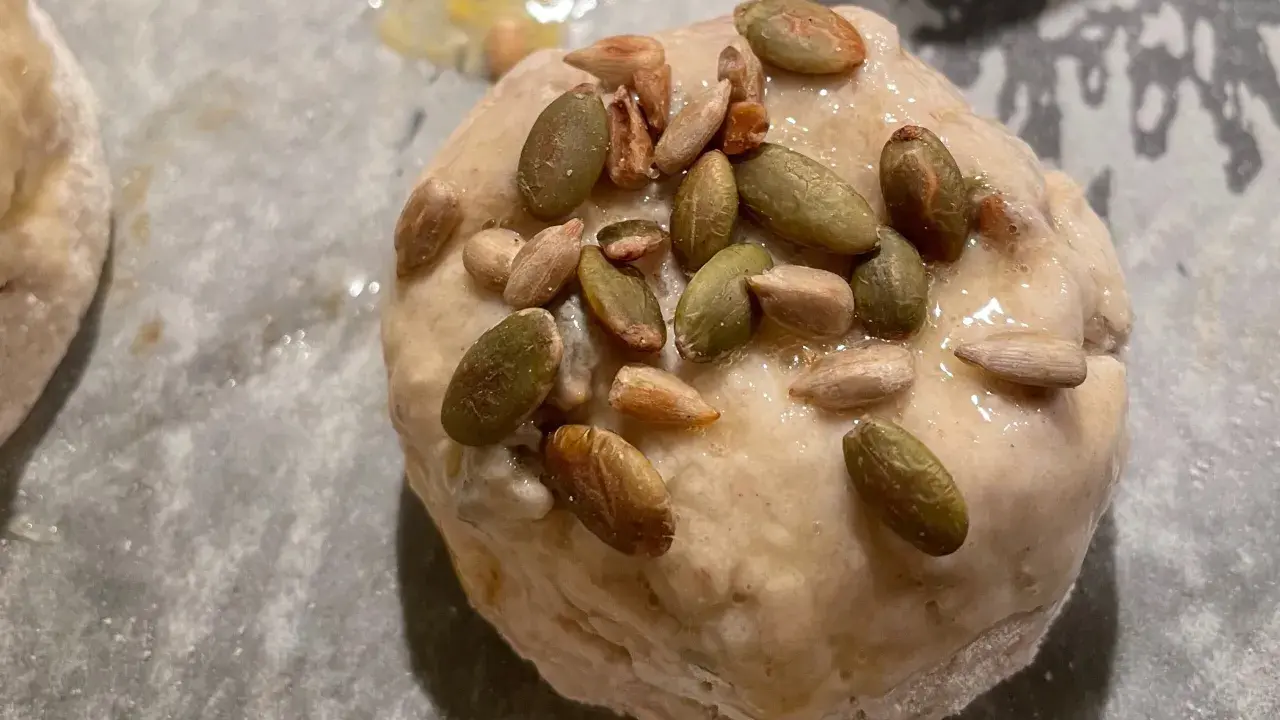En glutenfri fralla med pumpa- och solrosfrön på en bakplåt.
