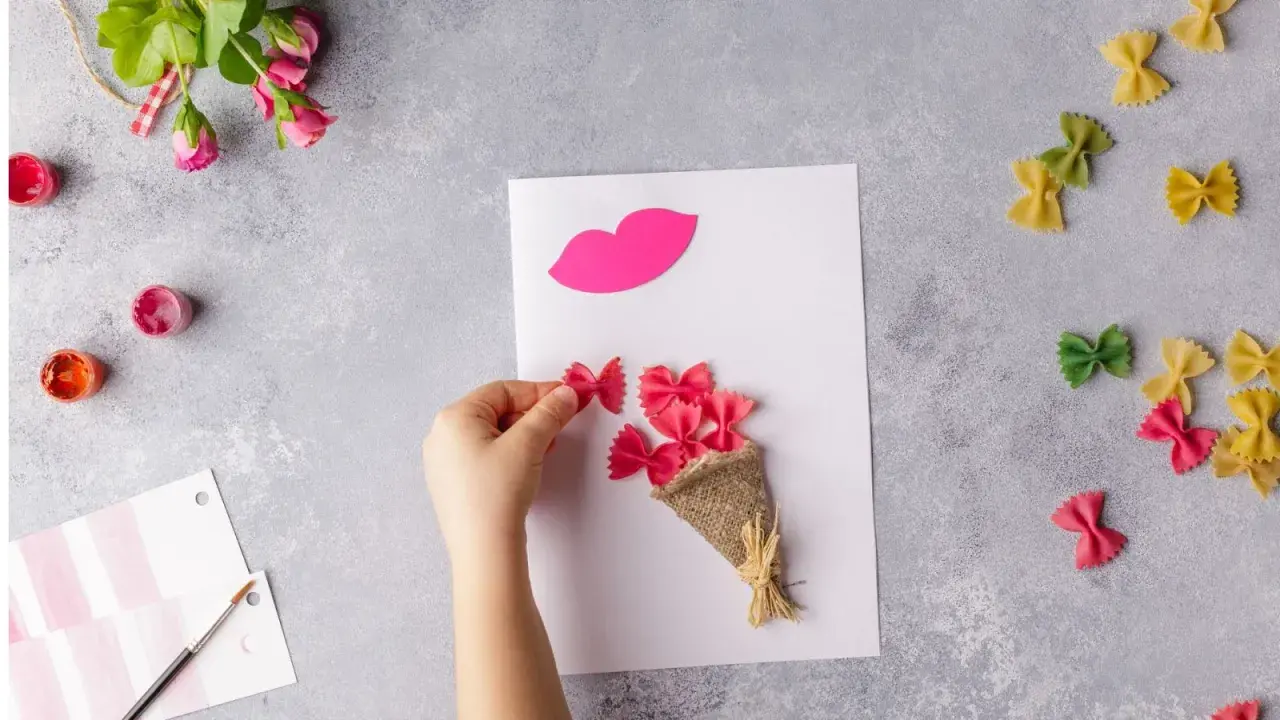 Manos creando flores manualidades con pasta de moño rosa, un ramo y labios de papel.