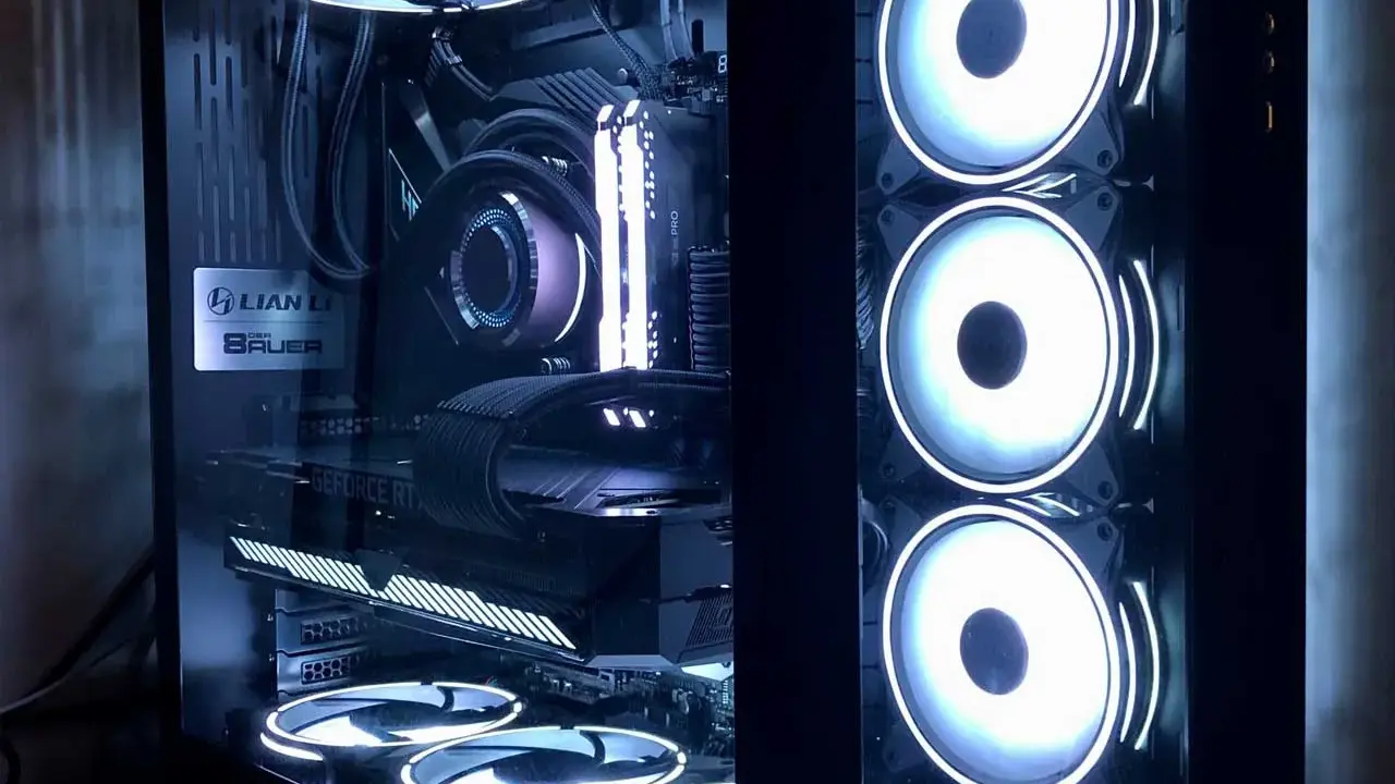 Intérieur d'un PC gamer avec éclairage RGB. On distingue la carte graphique, la carte mère, le système de refroidissement liquide et plusieurs ventilateurs. L'alimentation PC est bien visible.