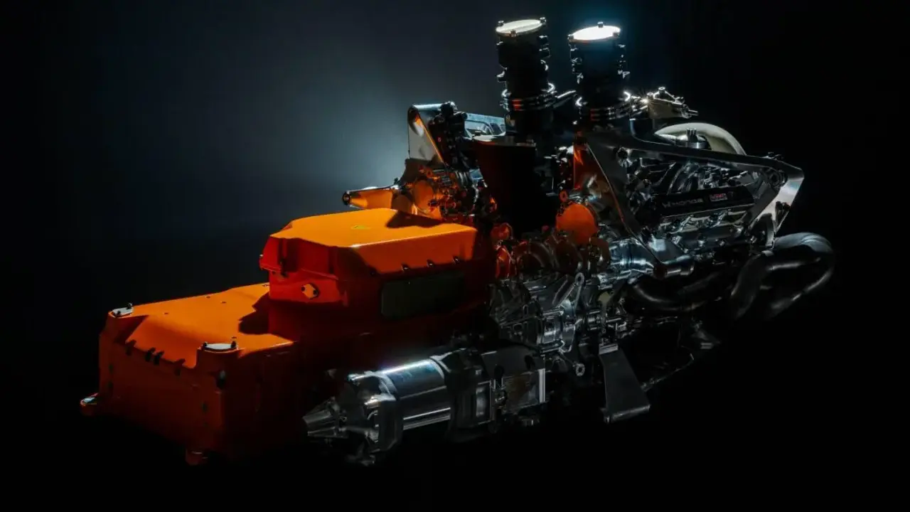 Un vistazo a los futuros motores F1 2026: un complejo sistema híbrido con componentes naranjas y metálicos, listo para la velocidad.