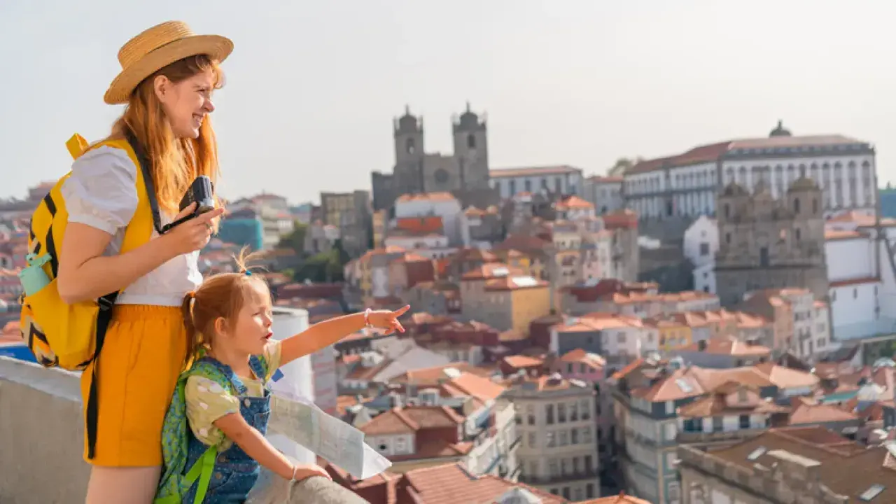 Una madre y su hija disfrutan de las vistas de Oporto con niños, señalando la ciudad histórica.