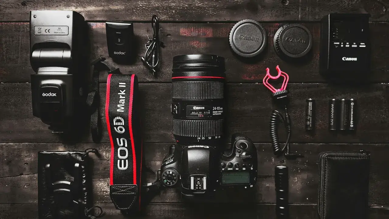 Zestaw fotograficzny: aparat Canon EOS 6D Mark II z obiektywem, lampa błyskowa, baterie i akcesoria. Podstawa aparatu fotograficznego gotowa do pracy.