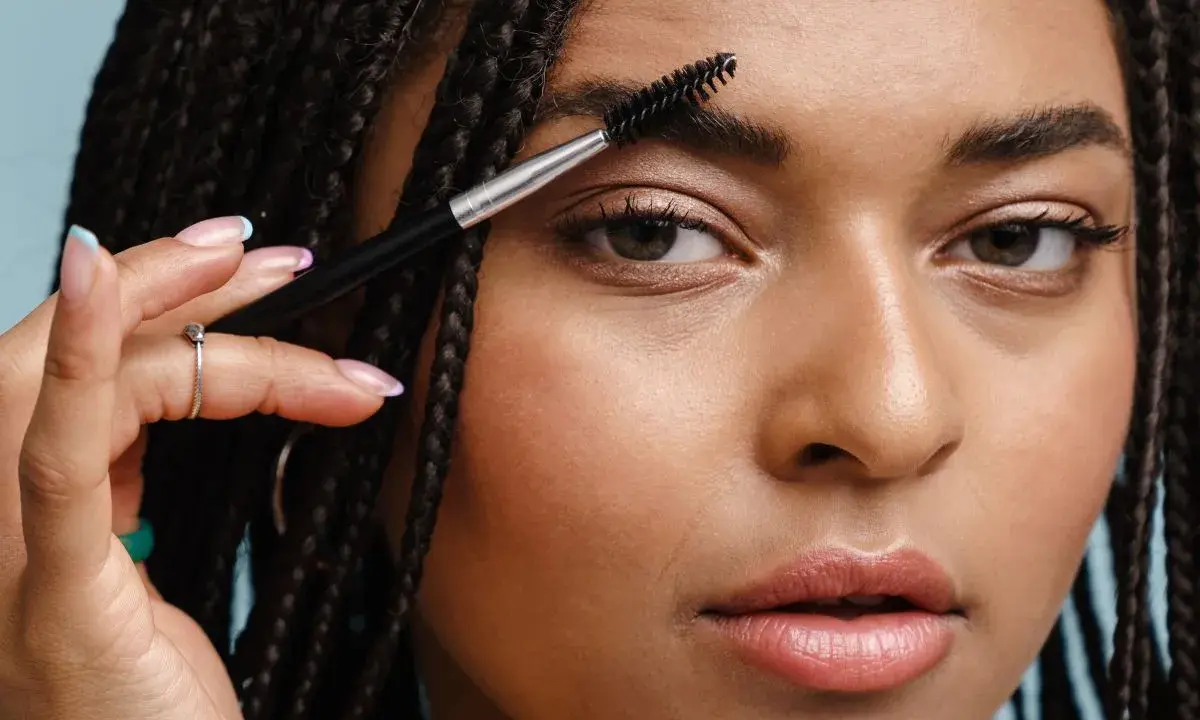 Une femme utilise une brosse pour coiffer son sourcil. La repousse d'un sourcil est une question de patience.