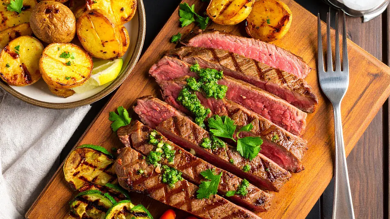 Saftig flankstek, perfekt grillad och skivad, serveras med klyftpotatis och grillade grönsaker. Ett fantastiskt flankstek recept för en härlig middag.