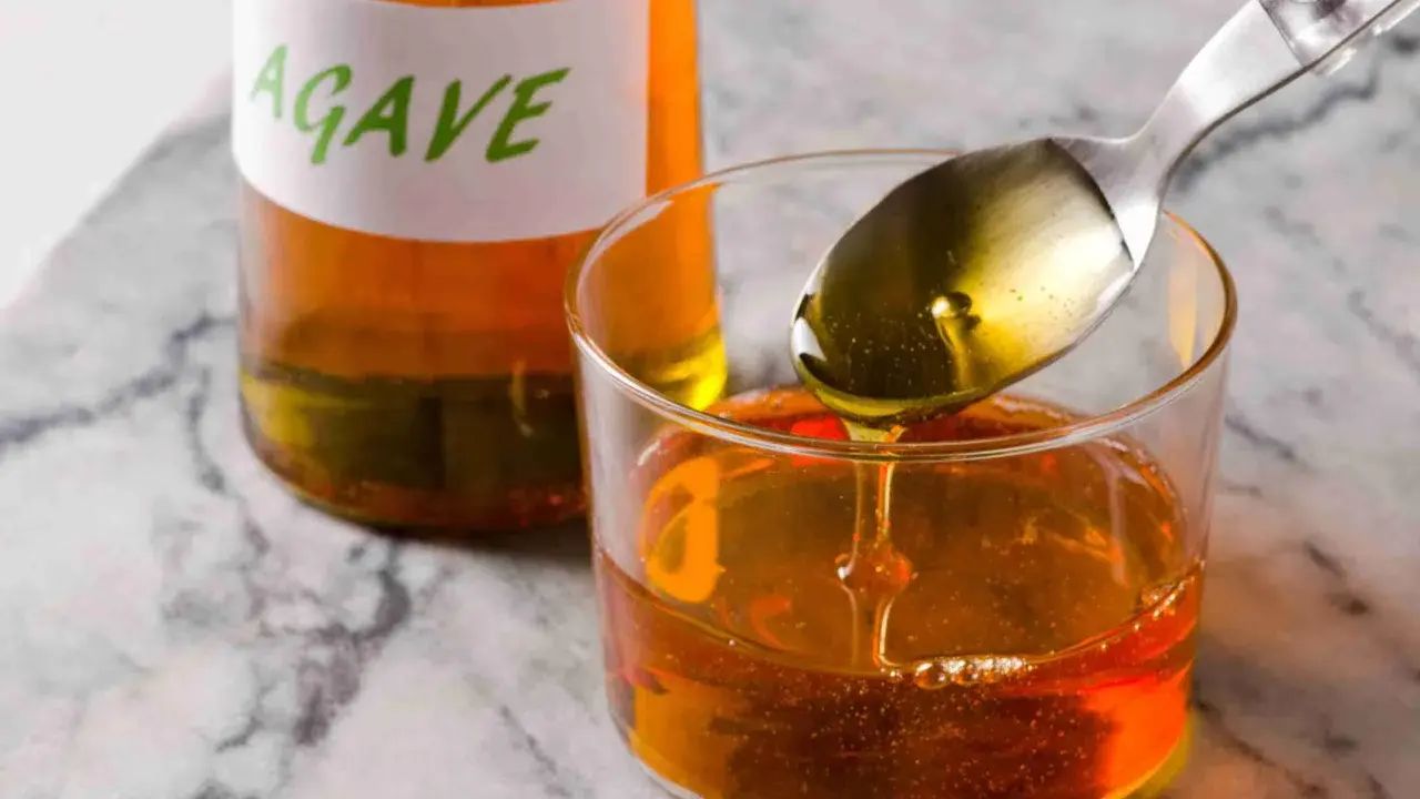Sirope de agave en un vaso, con una cuchara vertiendo más. Ideal para endulzar recetas durante el embarazo.