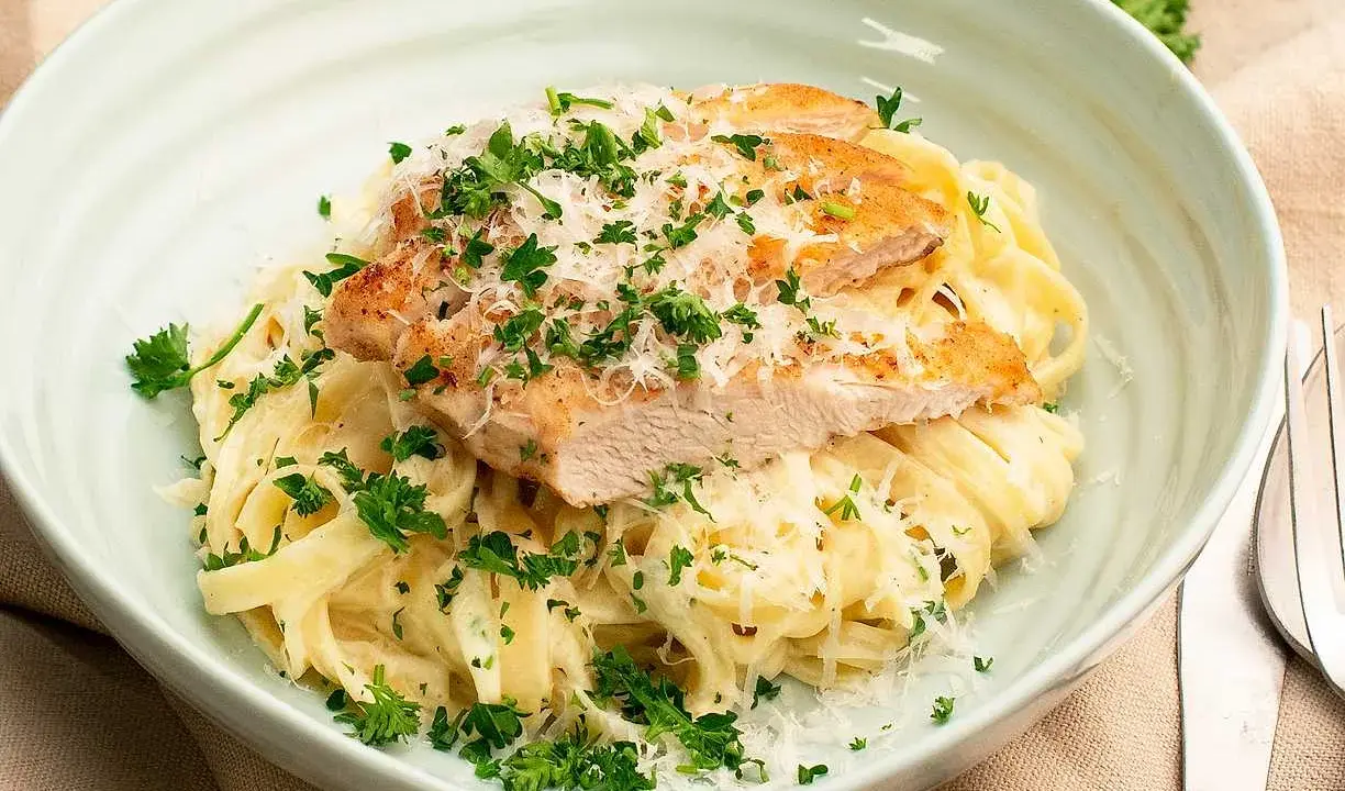 En krämig kyckling alfredo med tagliatelle, toppad med grillad kyckling, parmesan och färsk persilja. Ett perfekt recept för en snabb middag.