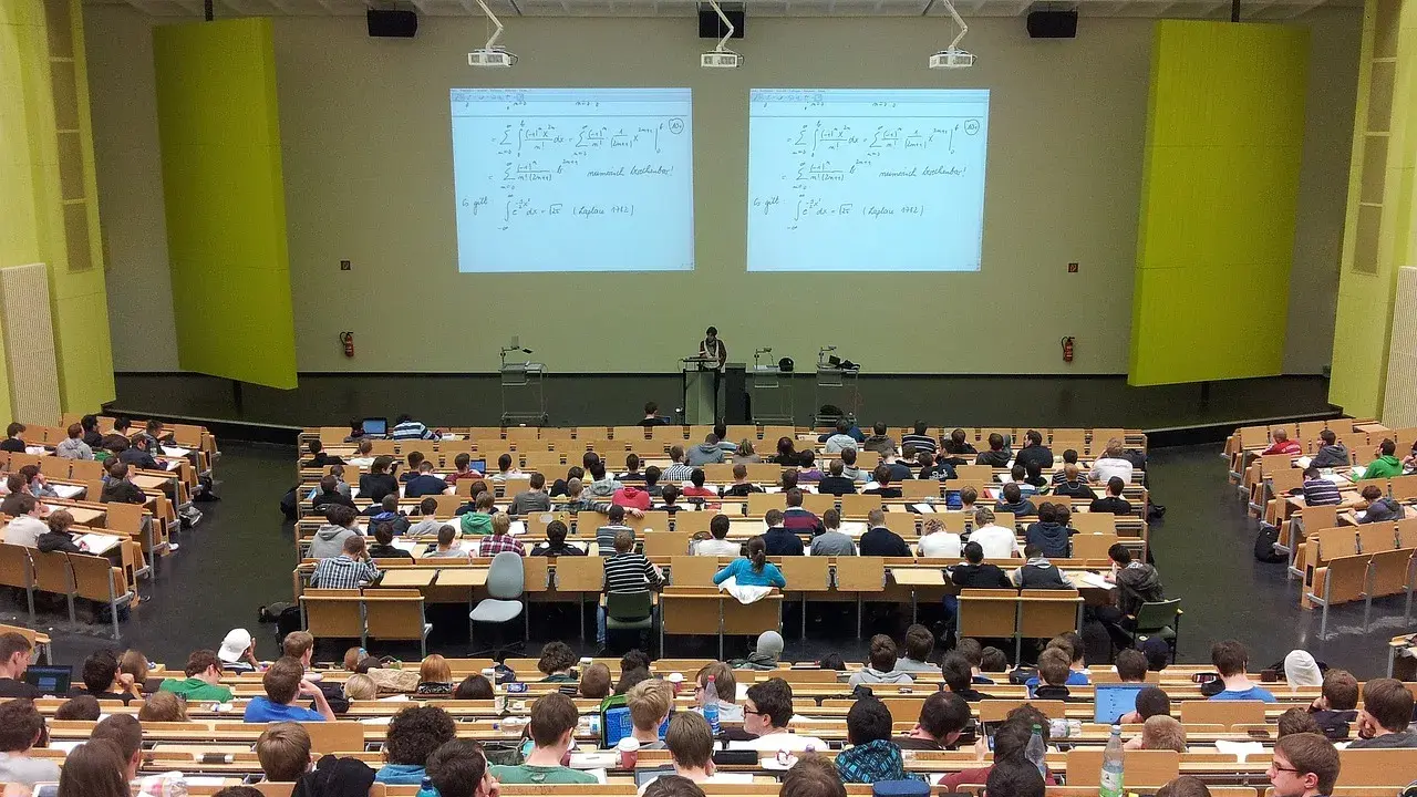 Wykład na uczelni w Szczecinie. Studenci słuchają wykładowcy na tle tablic z równaniami matematycznymi.