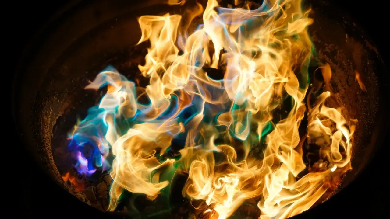 Fiamme danzanti in un braciere, con sfumature blu e verdi che si mescolano all'oro. Un'arte nel fotografare il fuoco.