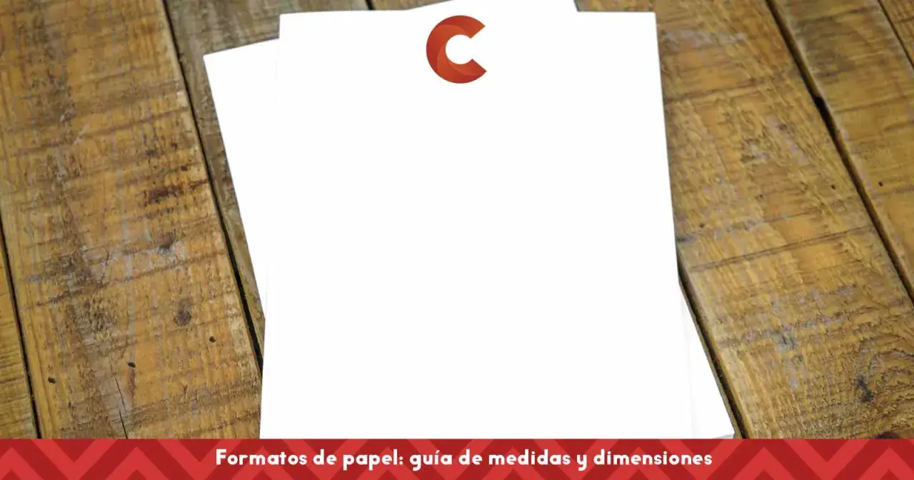 Dos hojas de papel blanco apiladas sobre una mesa de madera rústica. El papel para flyers está listo para ser diseñado.