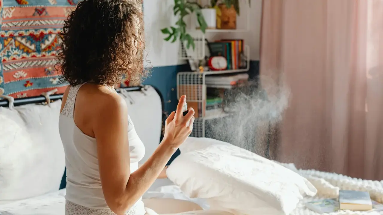 Mujer rocía almohada con spray para eliminar el olor fétido en una habitación.