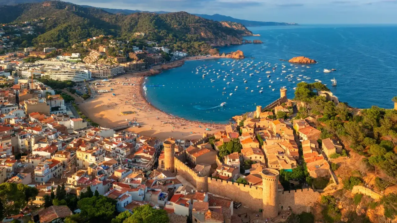 Widok na średniowieczne miasteczko z zamkiem i zatokę pełną łodzi. To idealne miejsce na odkrywanie atrakcji Costa Brava.