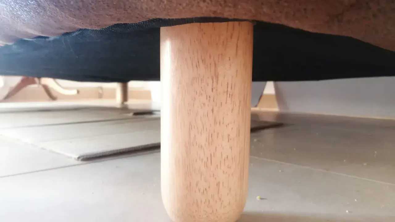 Una pata de madera de un canapé, mostrando cómo levantar un canapé del suelo para limpiarlo o moverlo.