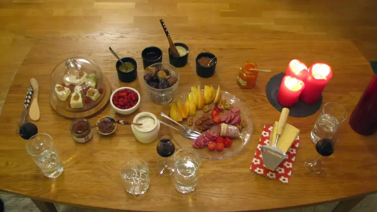 En härlig ostbricka jul med godsaker som frukt, nötter, korv och marmelad. Tre röda ljus lyser upp bordet.