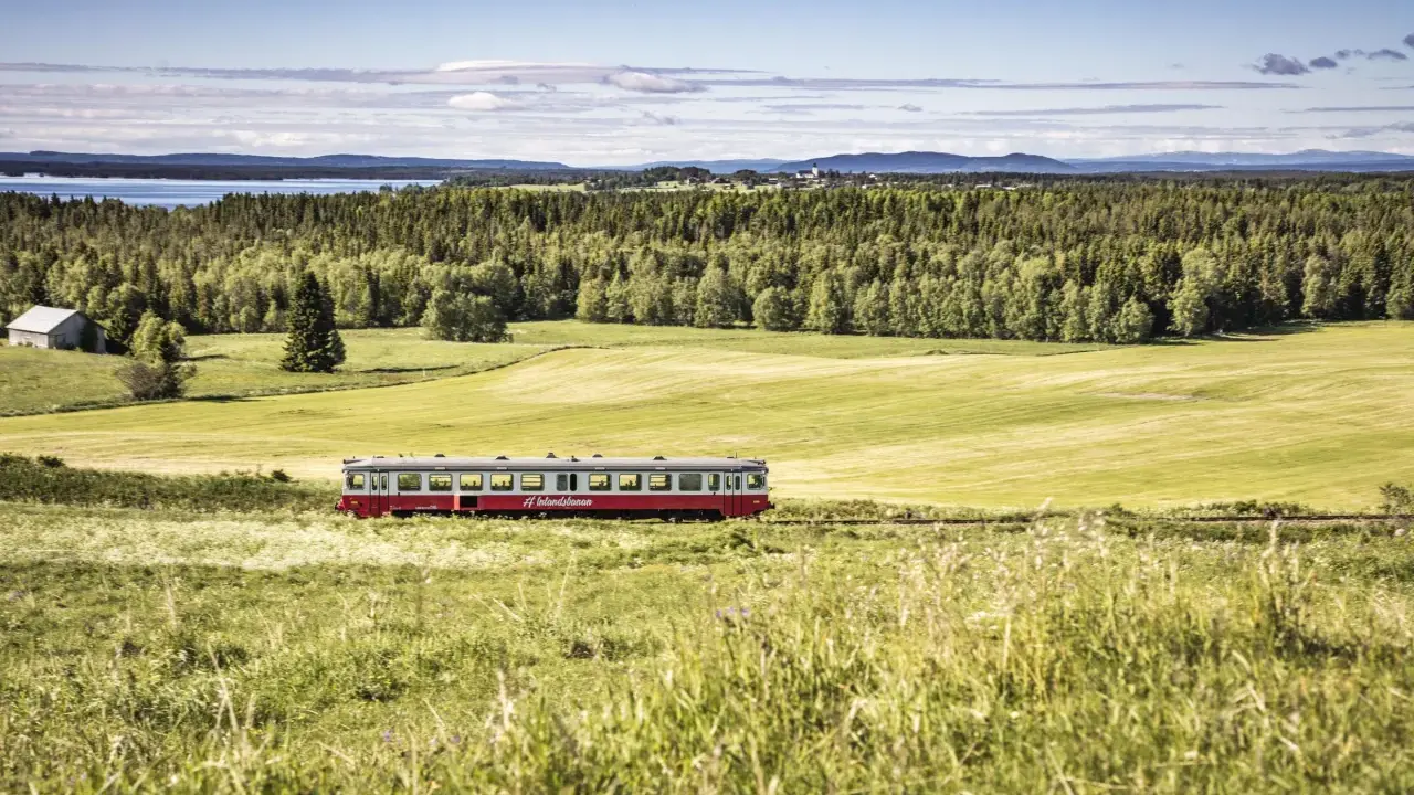 Roter Zug fährt durch grüne schwedische Landschaft. #Inlandsbanan.