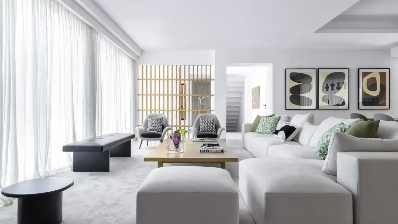 Elegante salón moderno. Sofá blanco modular, butacas grises y mesa de centro de madera. Combinar color gris en salón con toques verdes y arte abstracto.