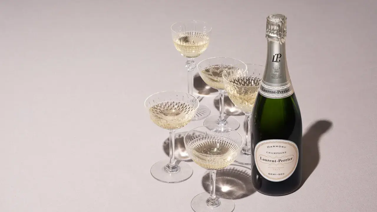 Flasche Laurent-Perrier Champagner neben gefüllten Gläsern. Ein süßer Champagner für besondere Anlässe.