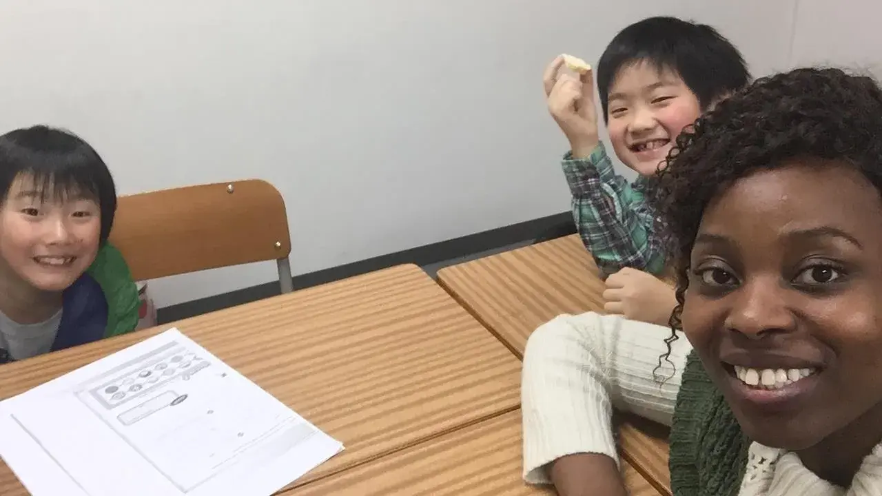 Fröhliche Kinder lernen Englisch. Eine Lehrerin gibt Nachhilfe auf Englisch.