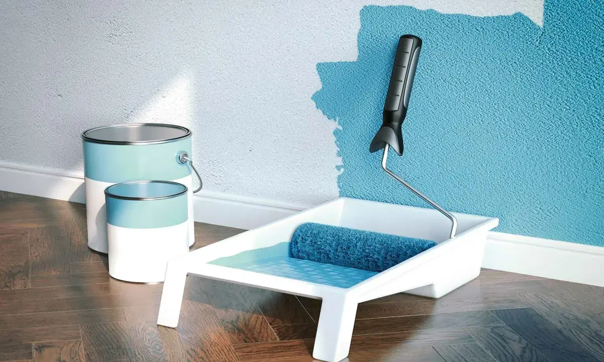 Latas de pintura plástica acrílica y rodillo listo para dar vida a una pared azul.