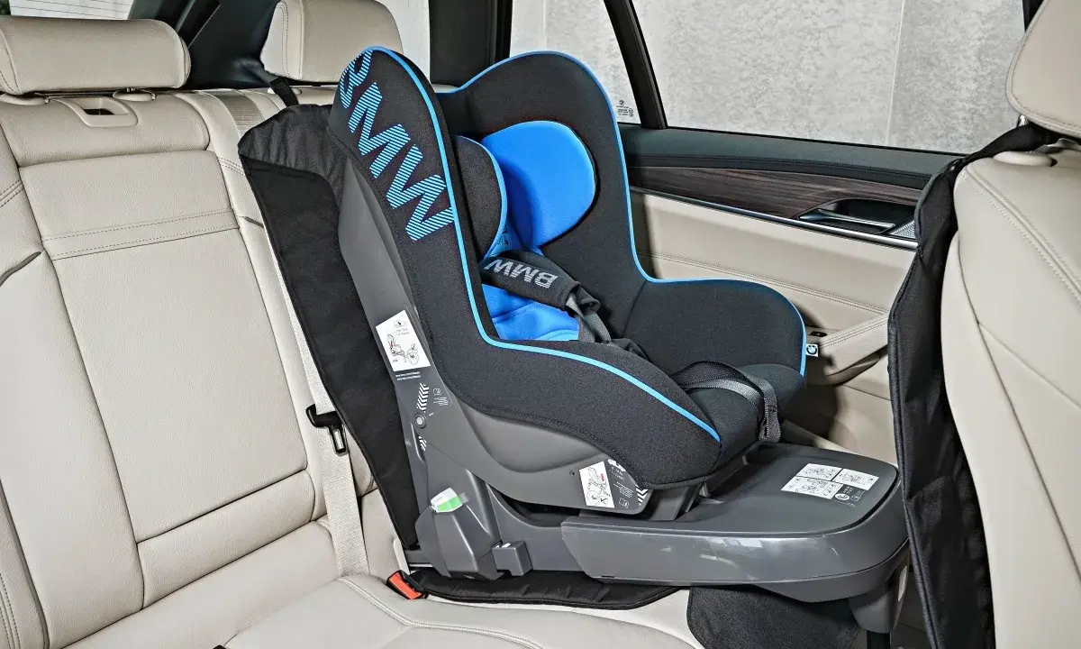 Fotelik dziecięcy BMW z systemem pasy isofix zamontowany na jasnej, skórzanej kanapie samochodowej.
