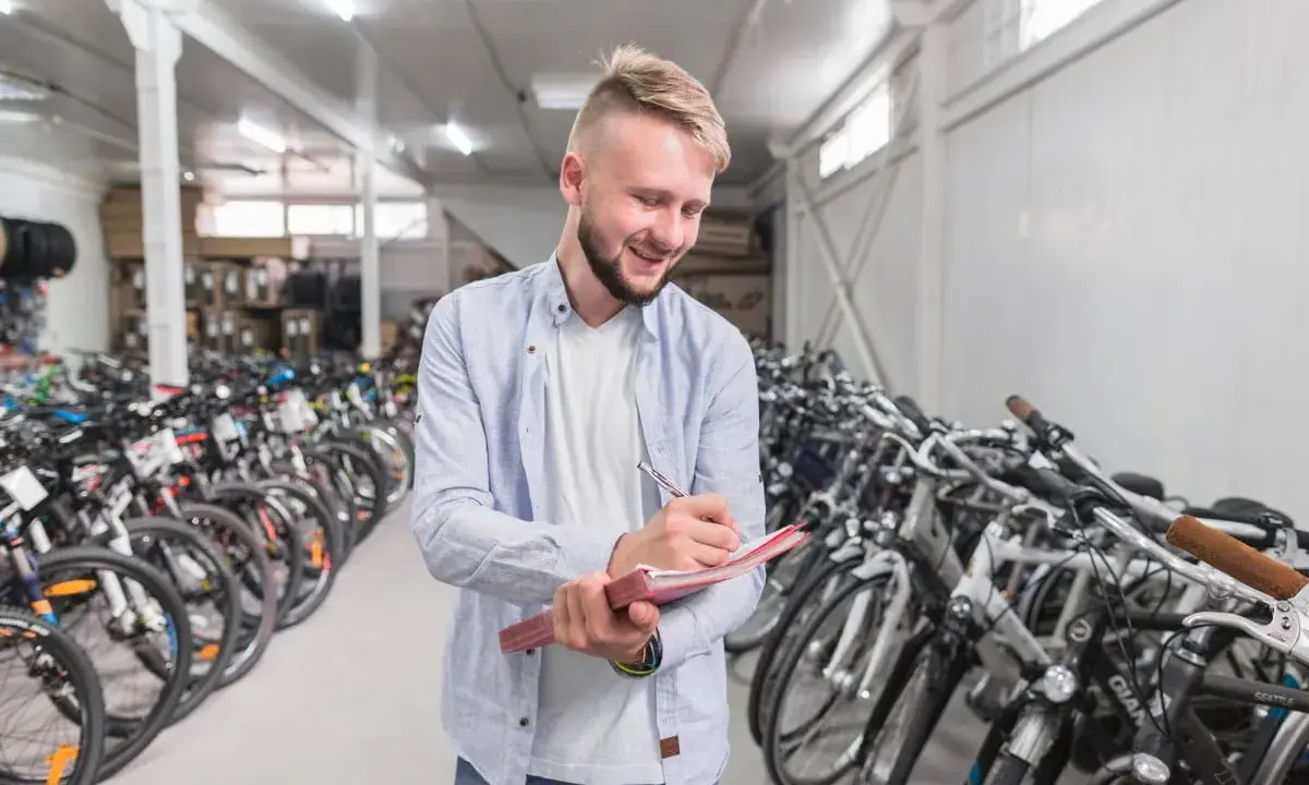 Uśmiechnięty sprzedawca notuje w zeszycie, otoczony rzędami rowerów amerykańskich marek.