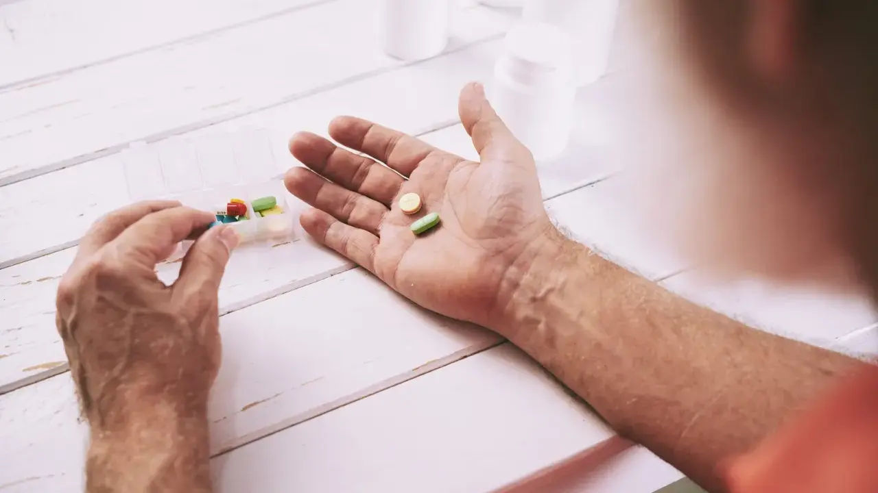 Mano che prende pillole da un portapillole. Speranza di guarigione con pembrolizumab.