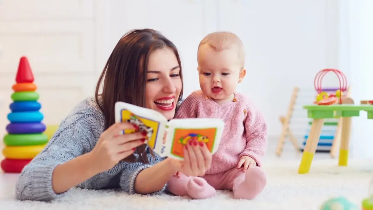Mama czyta książeczkę kolorową, a jej 2 letnie dziecko z zaciekawieniem słucha.