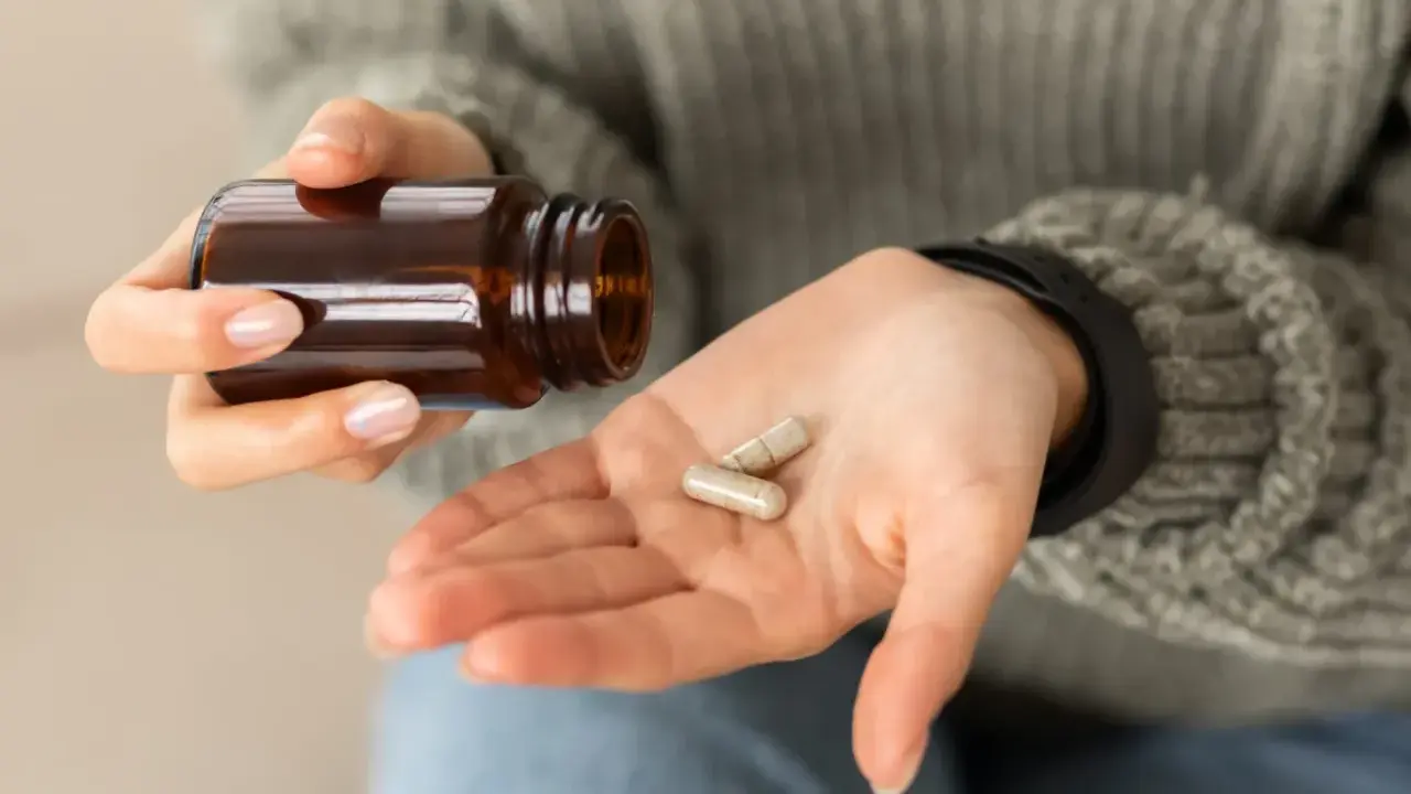 Dłoń z kapsułkami, które mogą wywołać biotyna skutki uboczne.