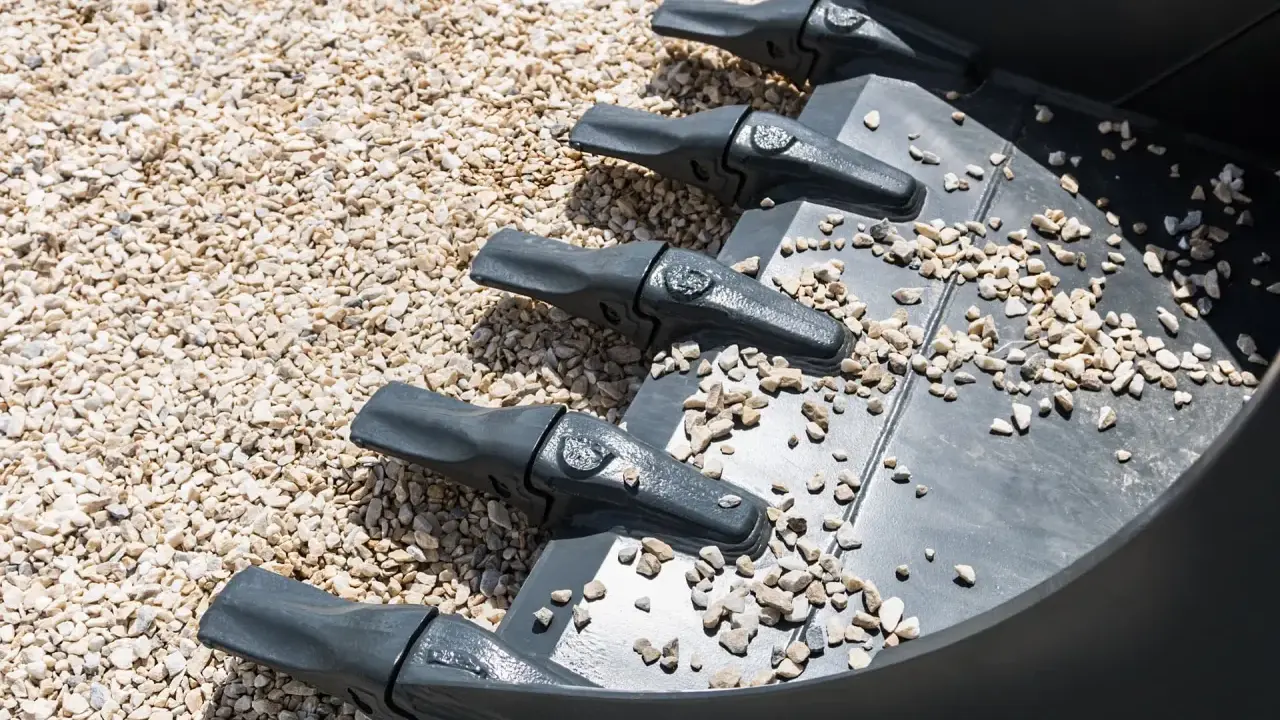 Dientes de excavadora sobre grava, una forma de como compactar tierra sin rodillo.