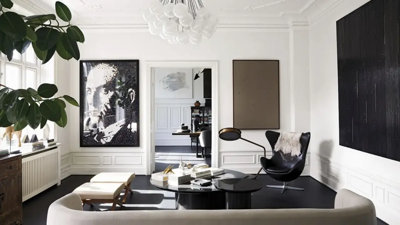 Ett elegant vardagsrum för ett hemma hos reportage. En stor porträttbild, en svart fåtölj och en rund soffa skapar en lyxig atmosfär.