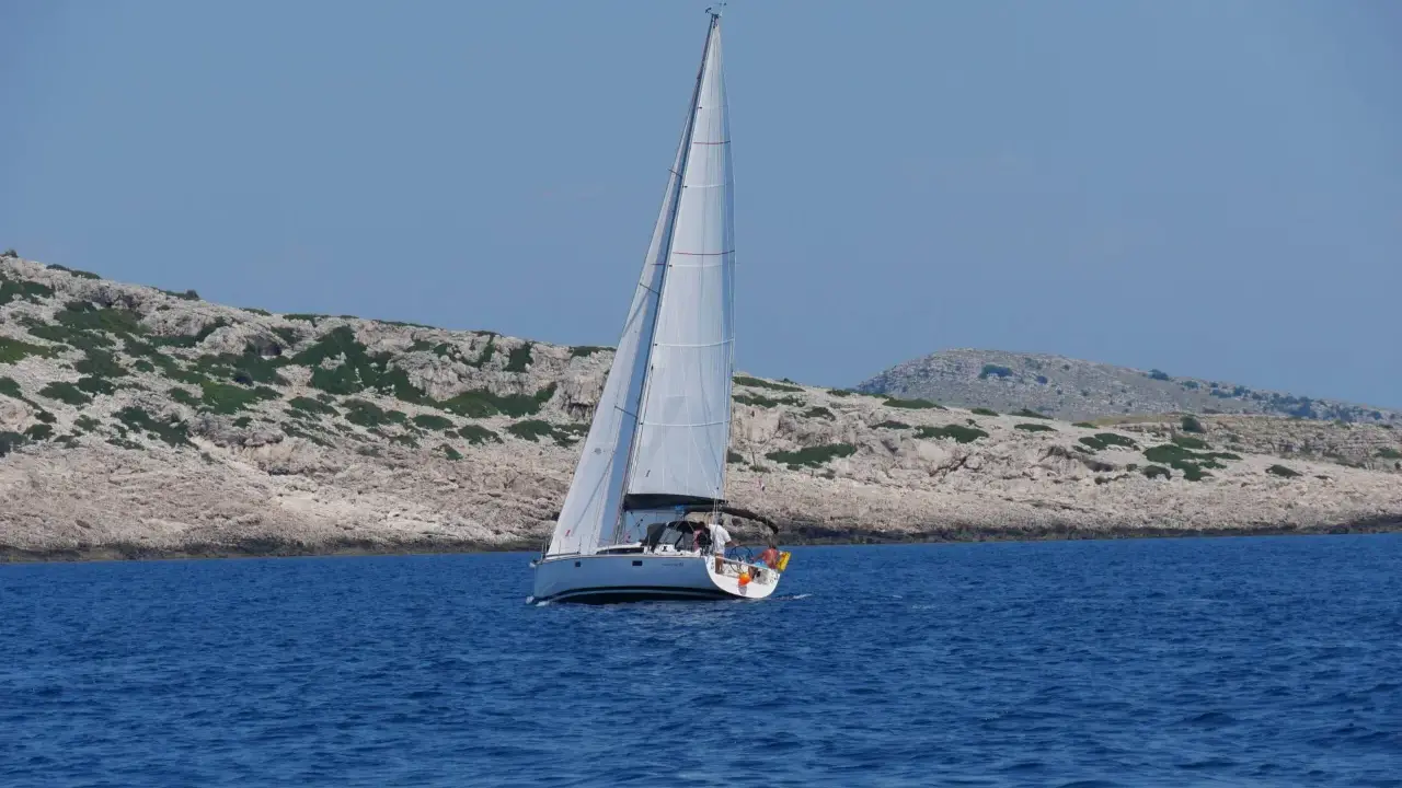 Segelboot gleitet durch das tiefblaue Wasser der kroatischen Kvarner Bucht, vorbei an felsigen, grünen Inseln.