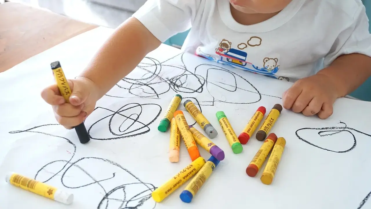 Bambino disegna con pastelli su foglio bianco. I disegni dei bambini sono un modo per esprimere emozioni, ma quando preoccuparsi?