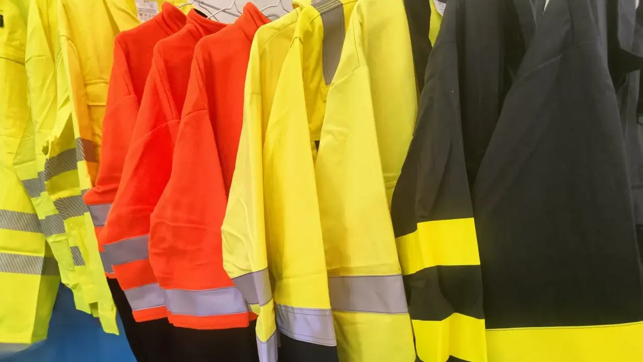Variedad de ropa de alta visibilidad normativa en colores amarillo, naranja y negro, con bandas reflectantes para garantizar la seguridad en entornos de trabajo.