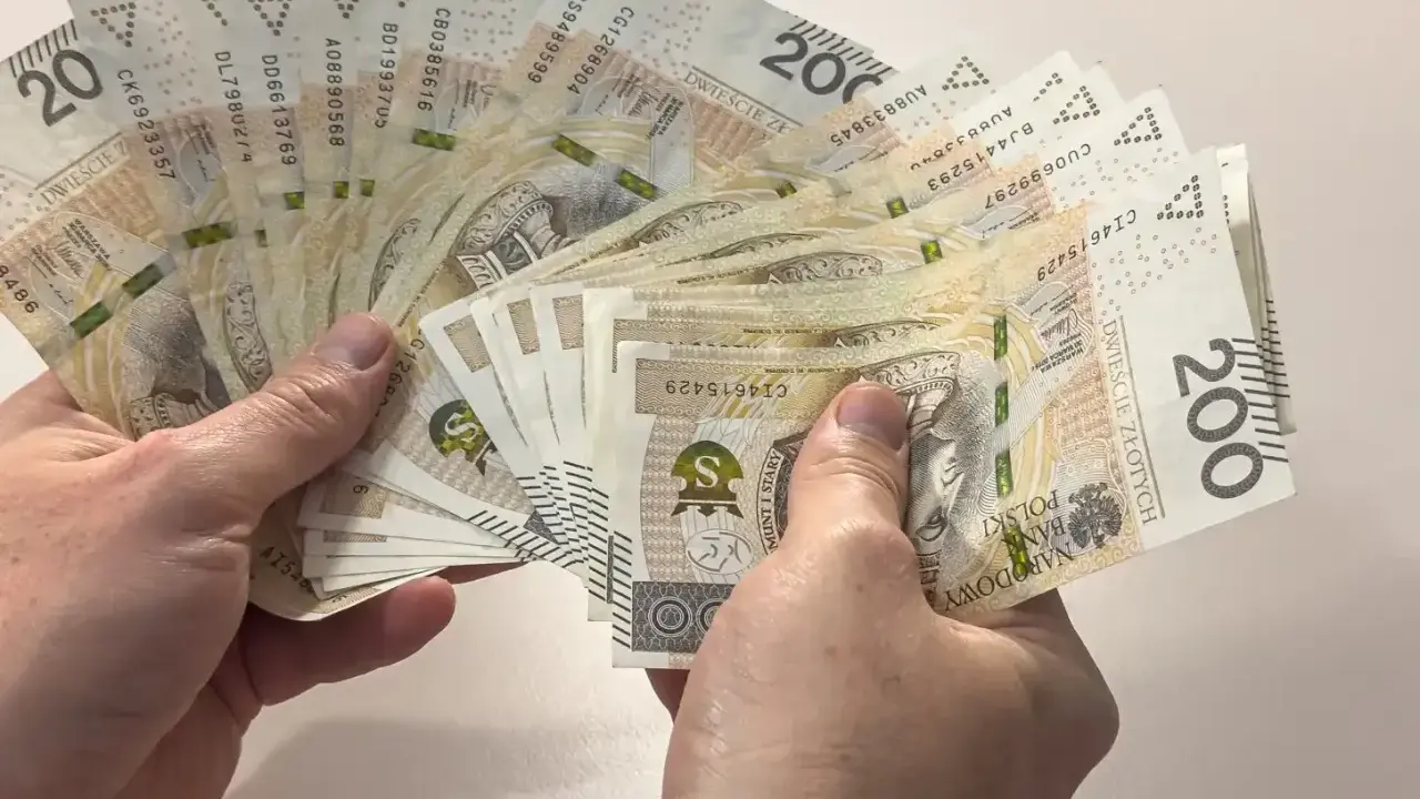 Dłonie trzymają wachlarz banknotów 200 zł. Zastanawiasz się, ile to brutto, jeśli 4200 netto to Twoja pensja?