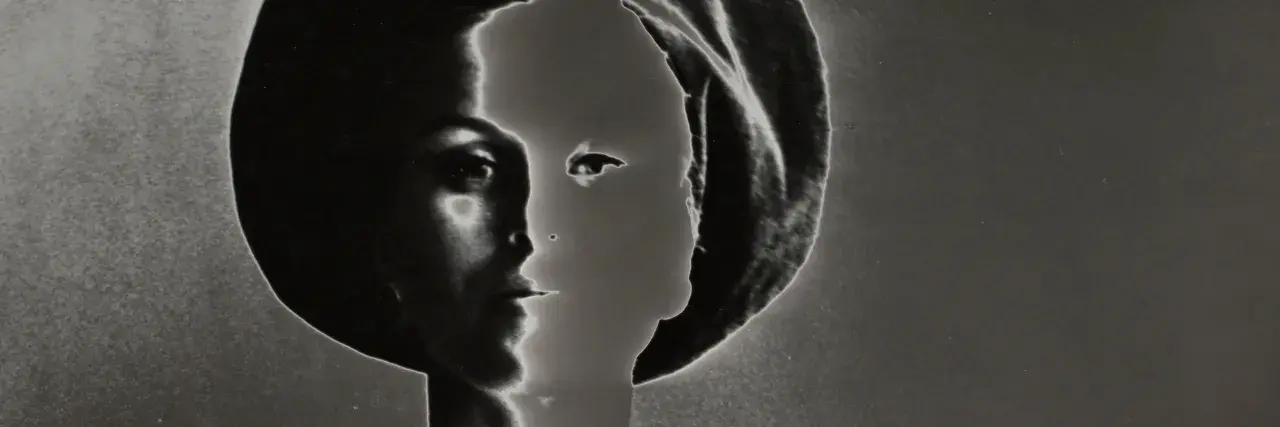 Volto femminile in profilo, un'icona di stile di Lillian Bassman, con un gioco di luci e ombre che ne esalta la misteriosa bellezza.