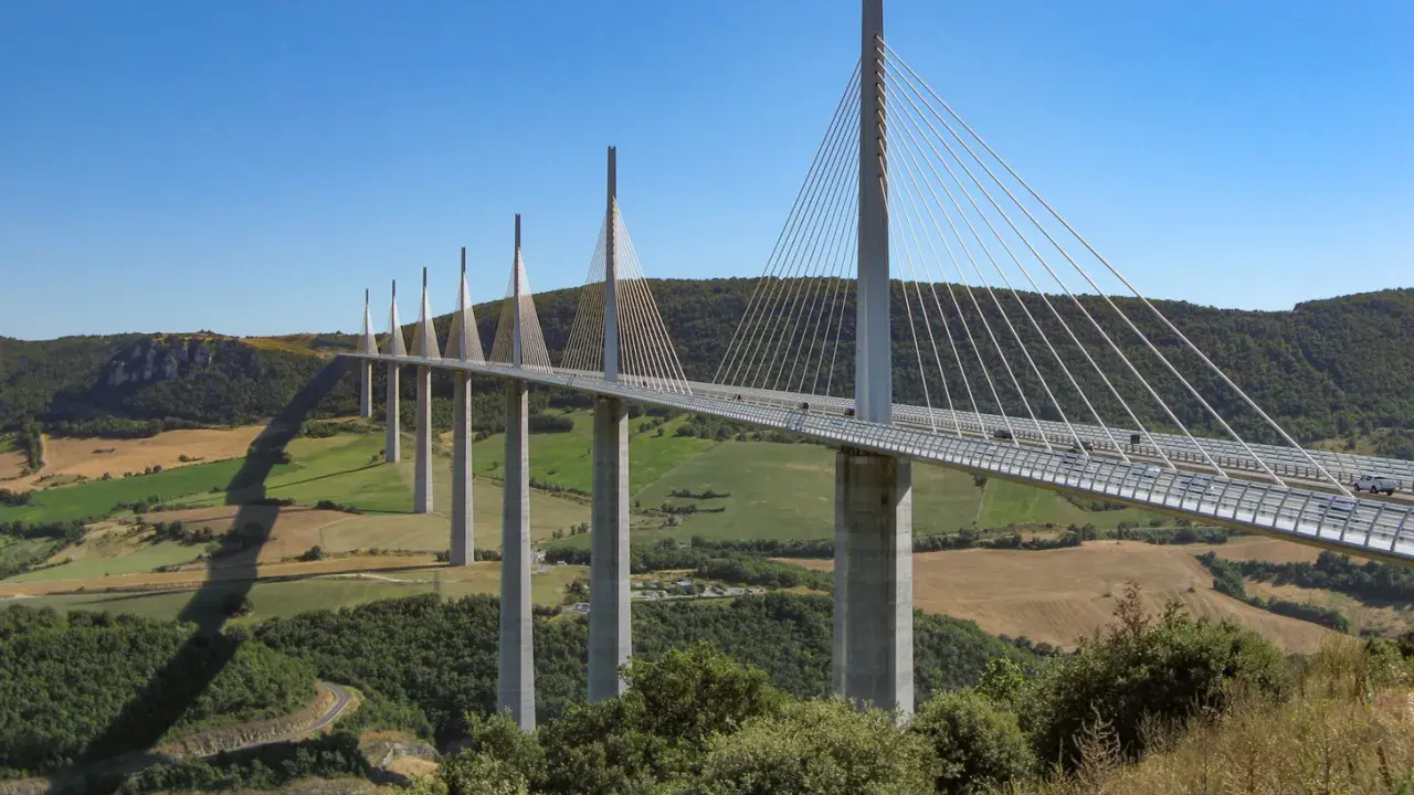 El viaducto de Millau, una maravilla de la ingeniería, se alza majestuoso sobre un valle verde. Su construcción desafía la gravedad.
