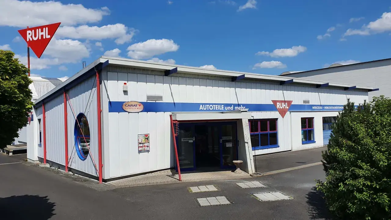 Gebäude von Ruhl Autoteile mit rotem Schild und blauem Schriftzug "AUTOTEILE und mehr...".