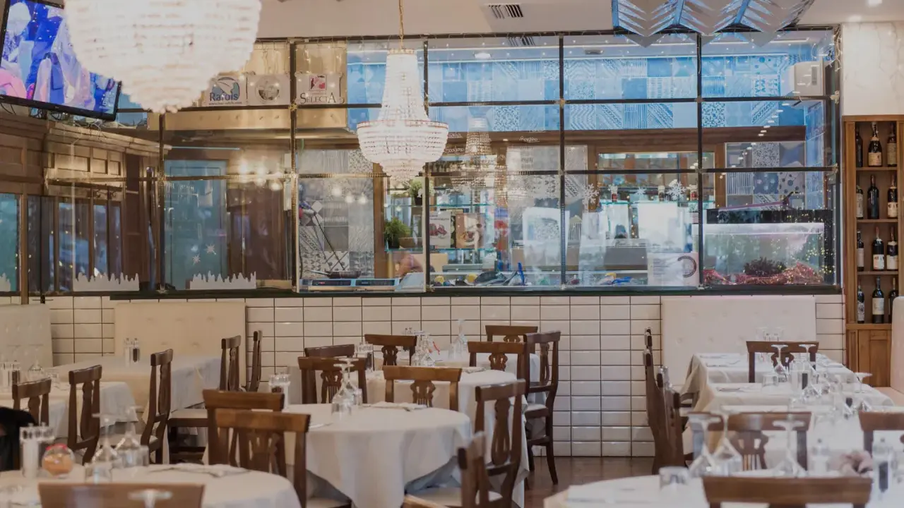 Interno del ristorante Amerigo a Rimini, con tavoli apparecchiati e lampadari eleganti.
