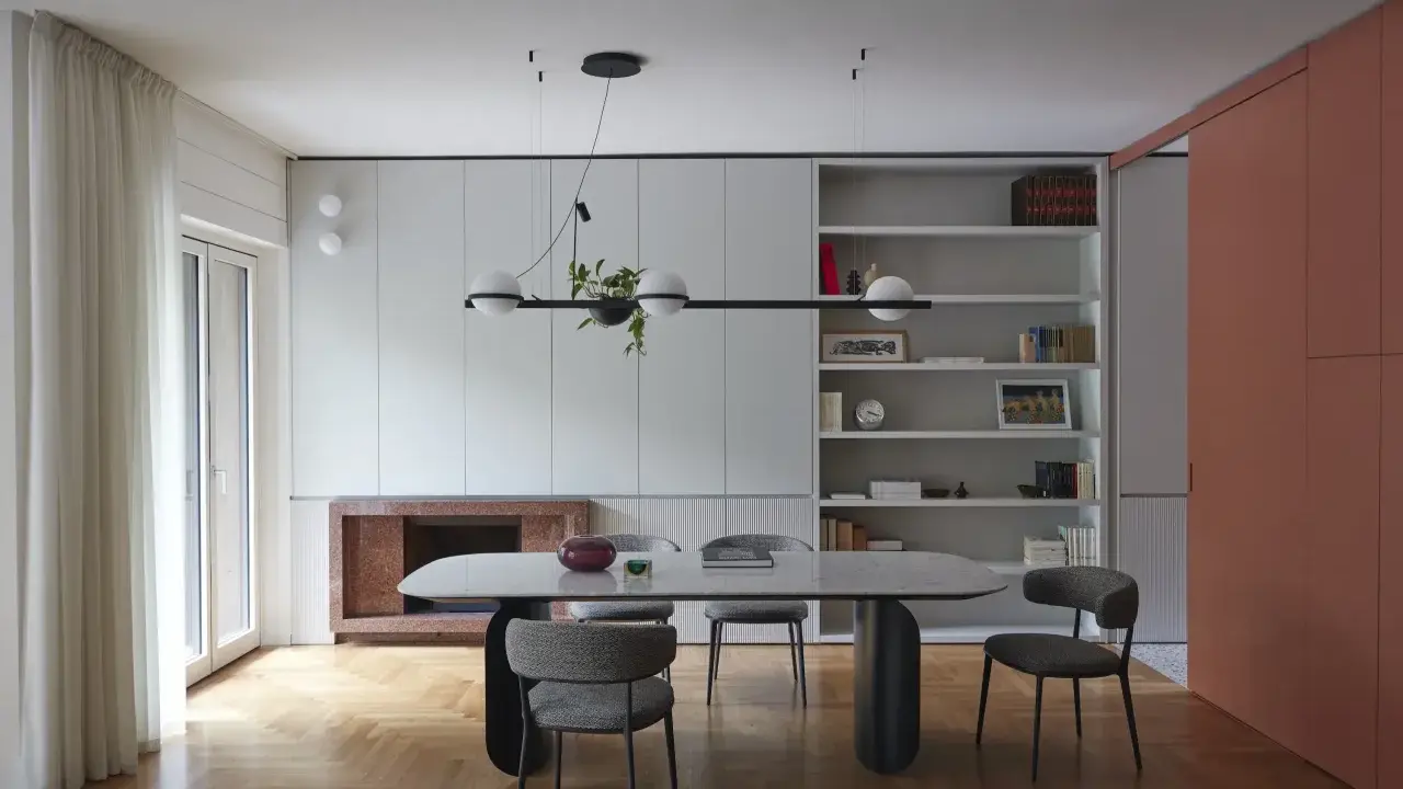 Sala da pranzo moderna con tavolo ovale, sedie imbottite e libreria a giorno. Le pareti grigio luminoso creano un'atmosfera sofisticata.
